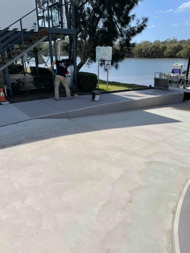 Worker resurfacing a concrete area beside a river